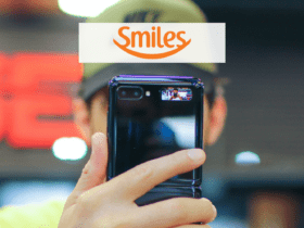 mão de homem branco segurando o samsung z flip com a logo da Smiles