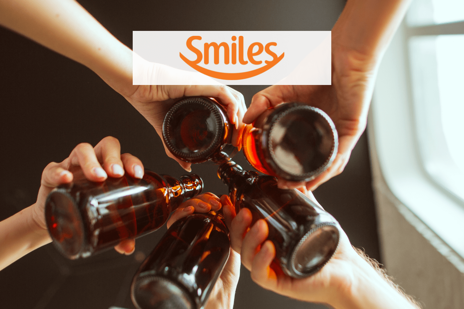 pessoas brindando garrafas com logo Smiles