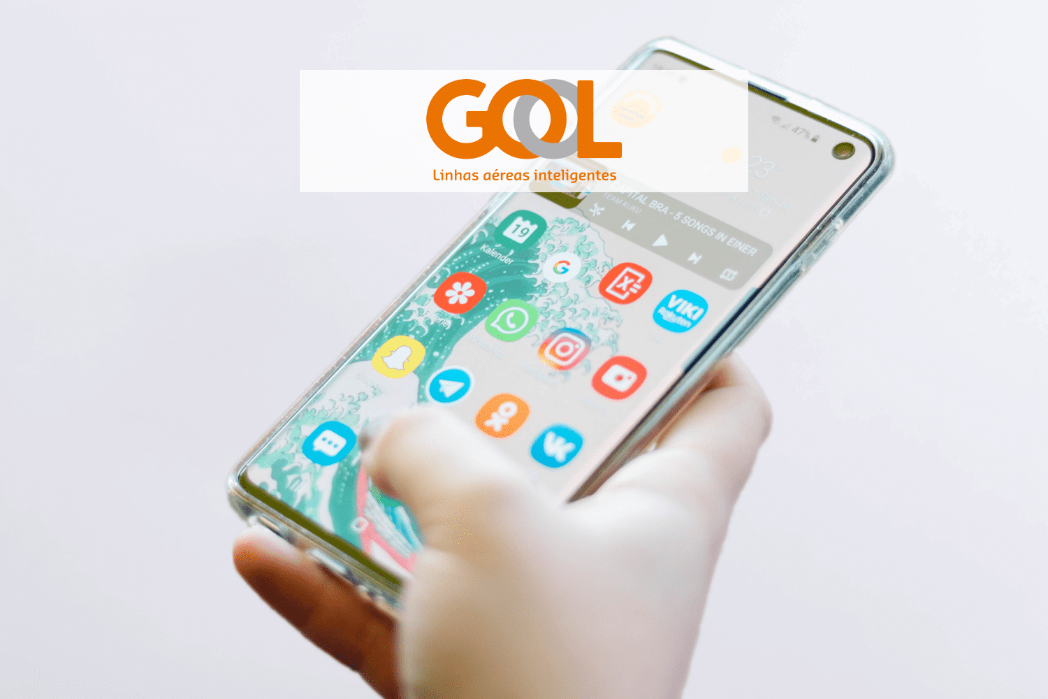 mão segurando um celular mexendo em aplicativos com logo Gol