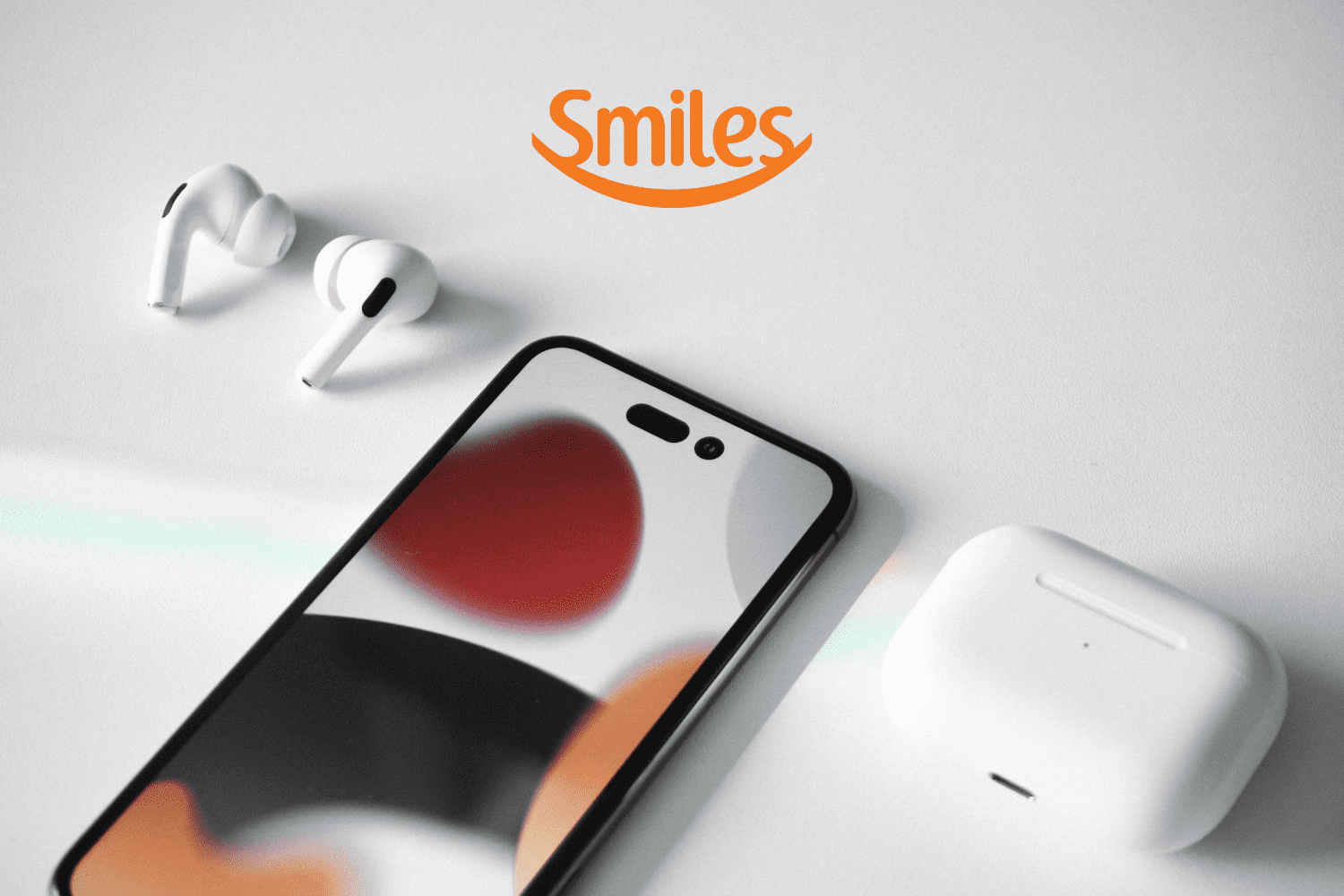 Iphone e fone de ouvido branco sobre uma mesa com logo Smiles