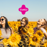 grupo de amigas sorrindo em um jardim de girassol com logo Livelo
