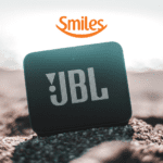 Caixa de som na areia da praia com logo Smiles