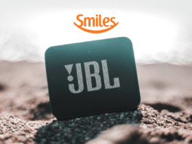 Caixa de som na areia da praia com logo Smiles