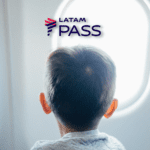 menino olhando na janela de um avião com a logo Latam Pass