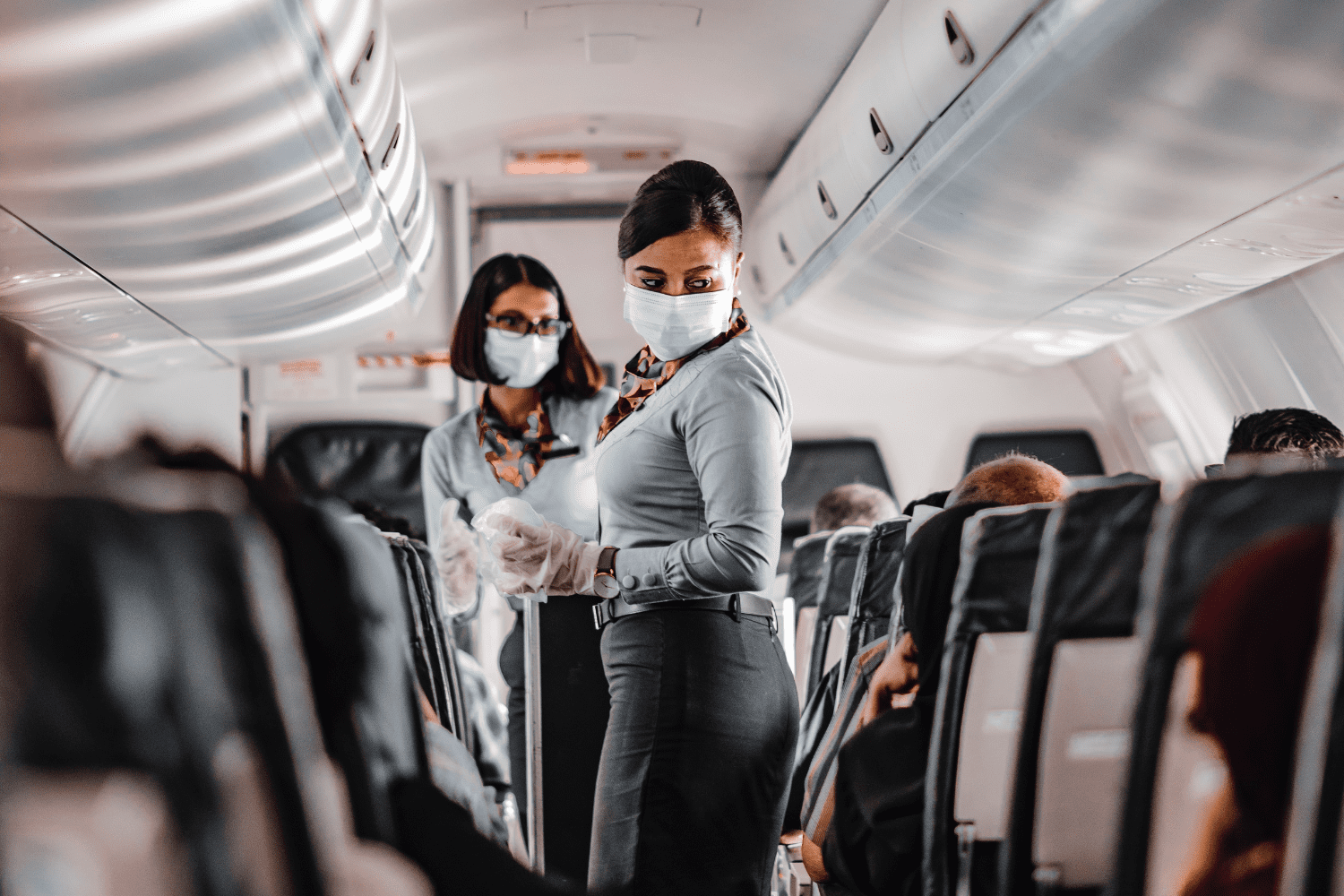 aeromoças utilizando máscaras no corredor do avião