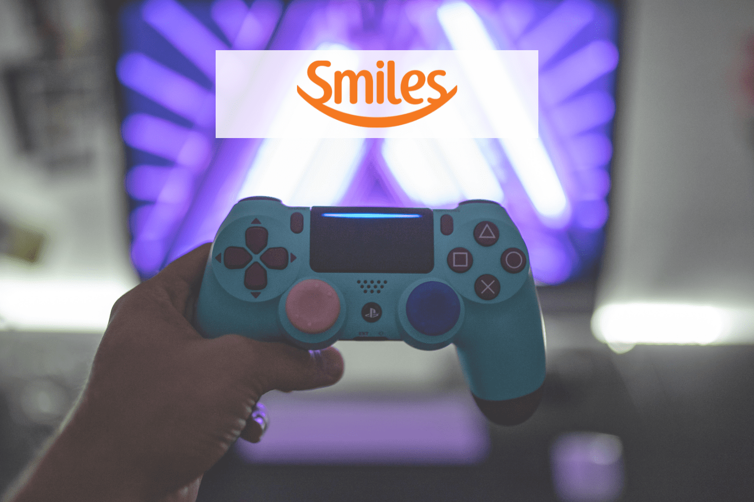 pessoa segurando controle de video game com logo Smiles