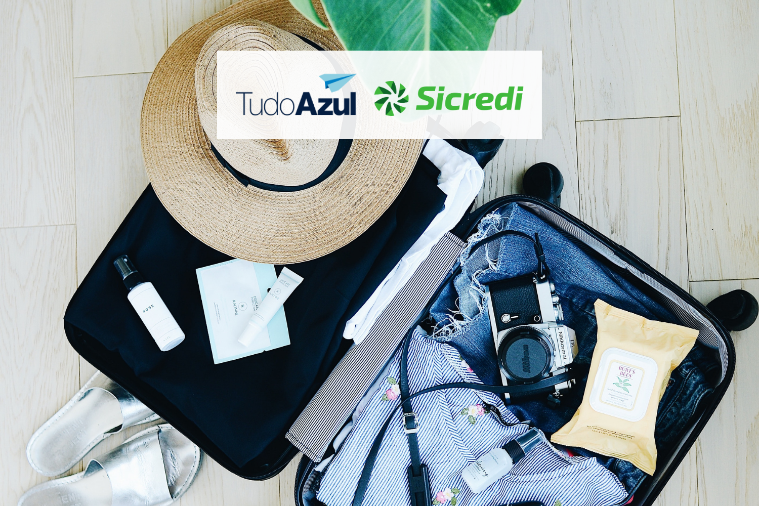 Mala de viagem com roupas e acessórios com logo TudoAzul e Sicredi