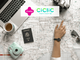 pessoa olhando um mapa de viagem com notebook, passaporte e câmeras com logo Livelo e Ciclic
