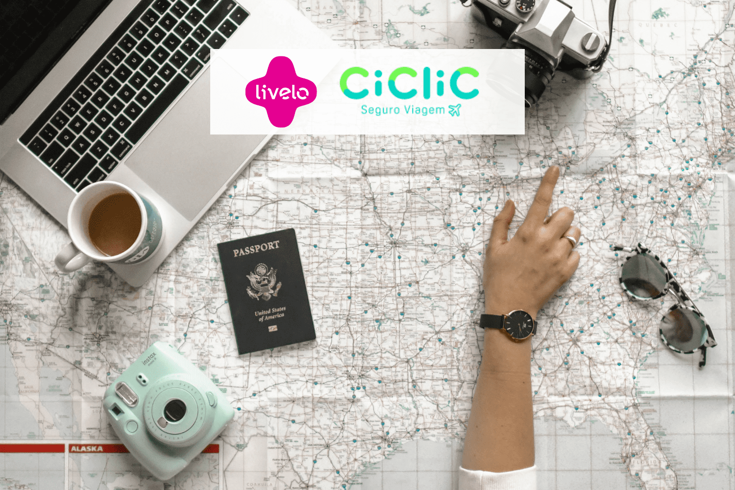 pessoa olhando um mapa de viagem com notebook, passaporte e câmeras com logo Livelo e Ciclic