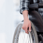 imagem da mão de uma pessoa cadeirante segurando a roda da cadeira