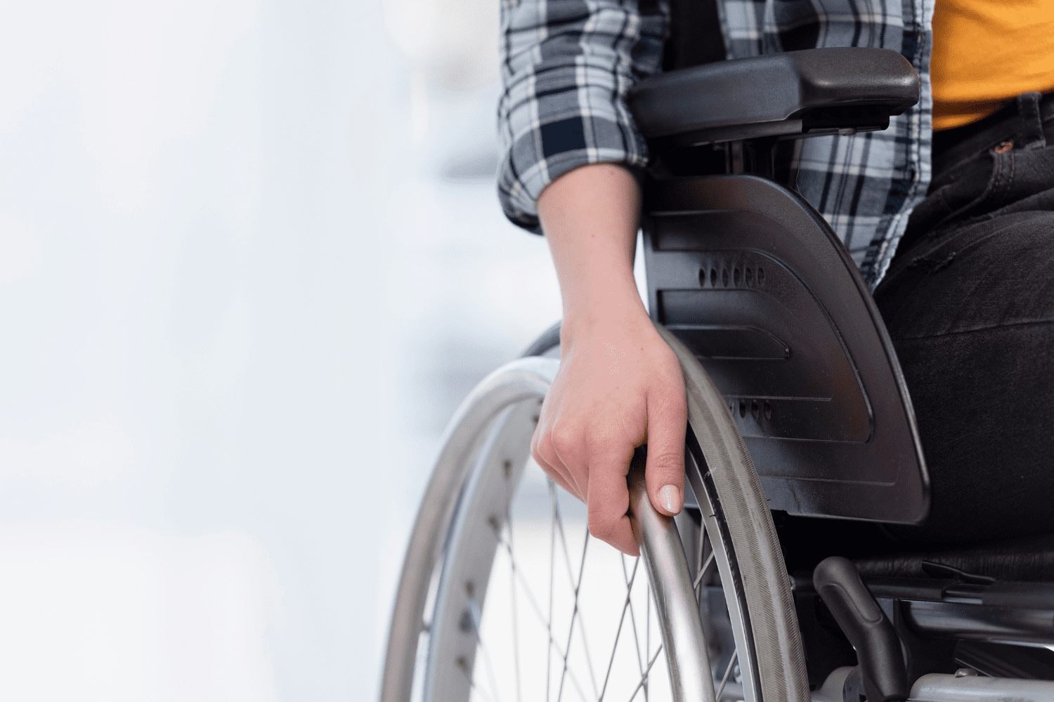 imagem da mão de uma pessoa cadeirante segurando a roda da cadeira