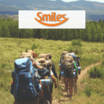 grupo de amigos com mochila de viagem fazendo uma trilha com logo Smiles