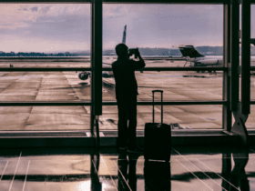 pessoa com bagagem no aeroporto tirando fotos dos aviões