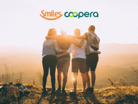 Amigos se abraçando feliz olhando para o horizonte com logo Smiles e Coopera Até 80% de bônus Smiles