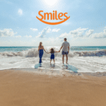 família em uma praia com logo Smiles Clube Smiles