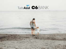 mulher com criança pequena indo em direção ao mar com logo TudoAzul e C6 Bank bônus TudoAzul