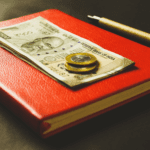 caderno vermelho com nota de dinheiro milhas aéreas