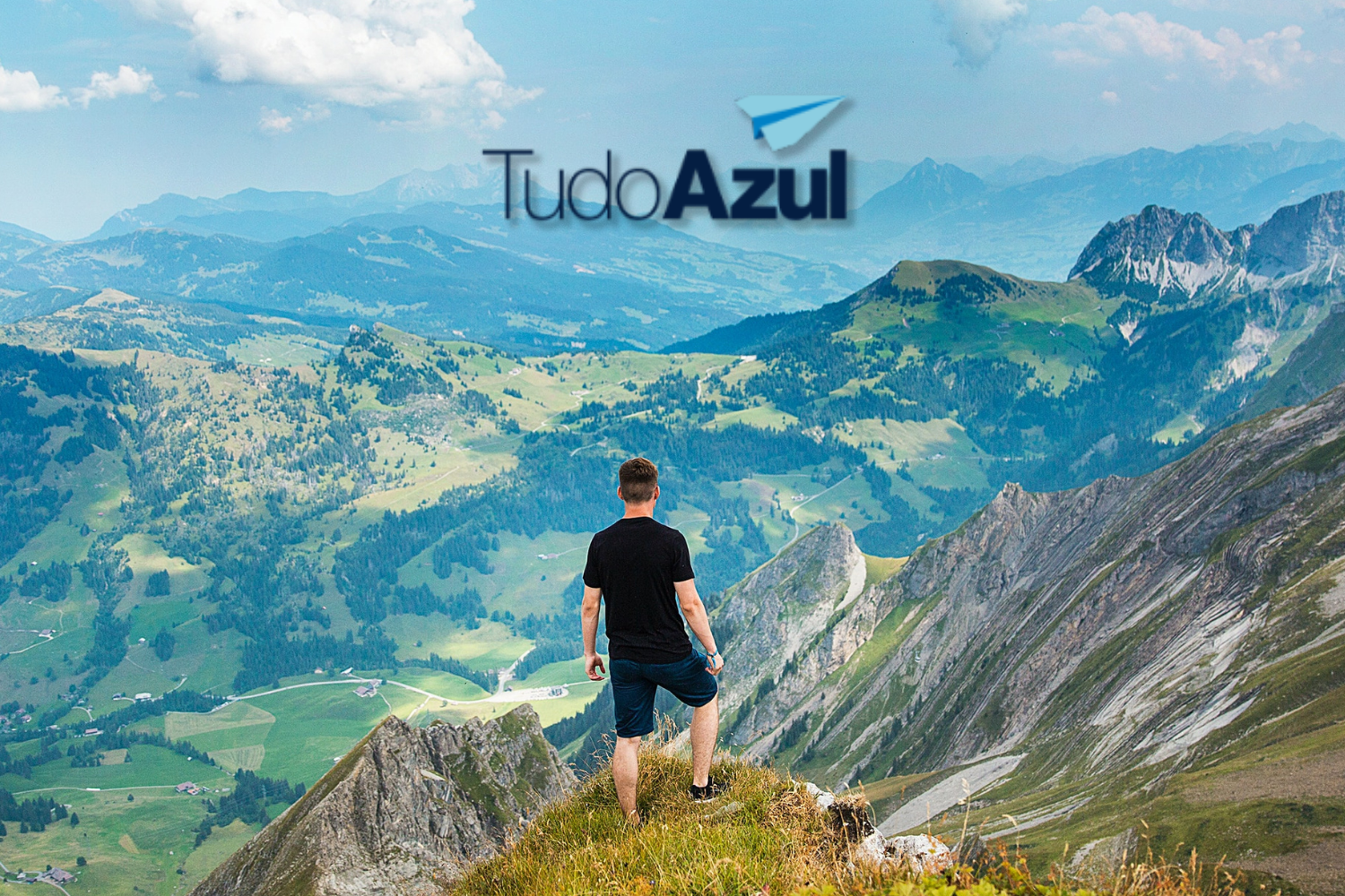 homem branco no topo de uma montanha com logo TudoAzul Clube TudoAzul