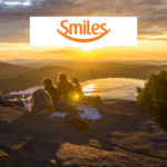 grupo de pessoas no topo de uma montanha olhando a vista com logo Smiles pontos Smiles