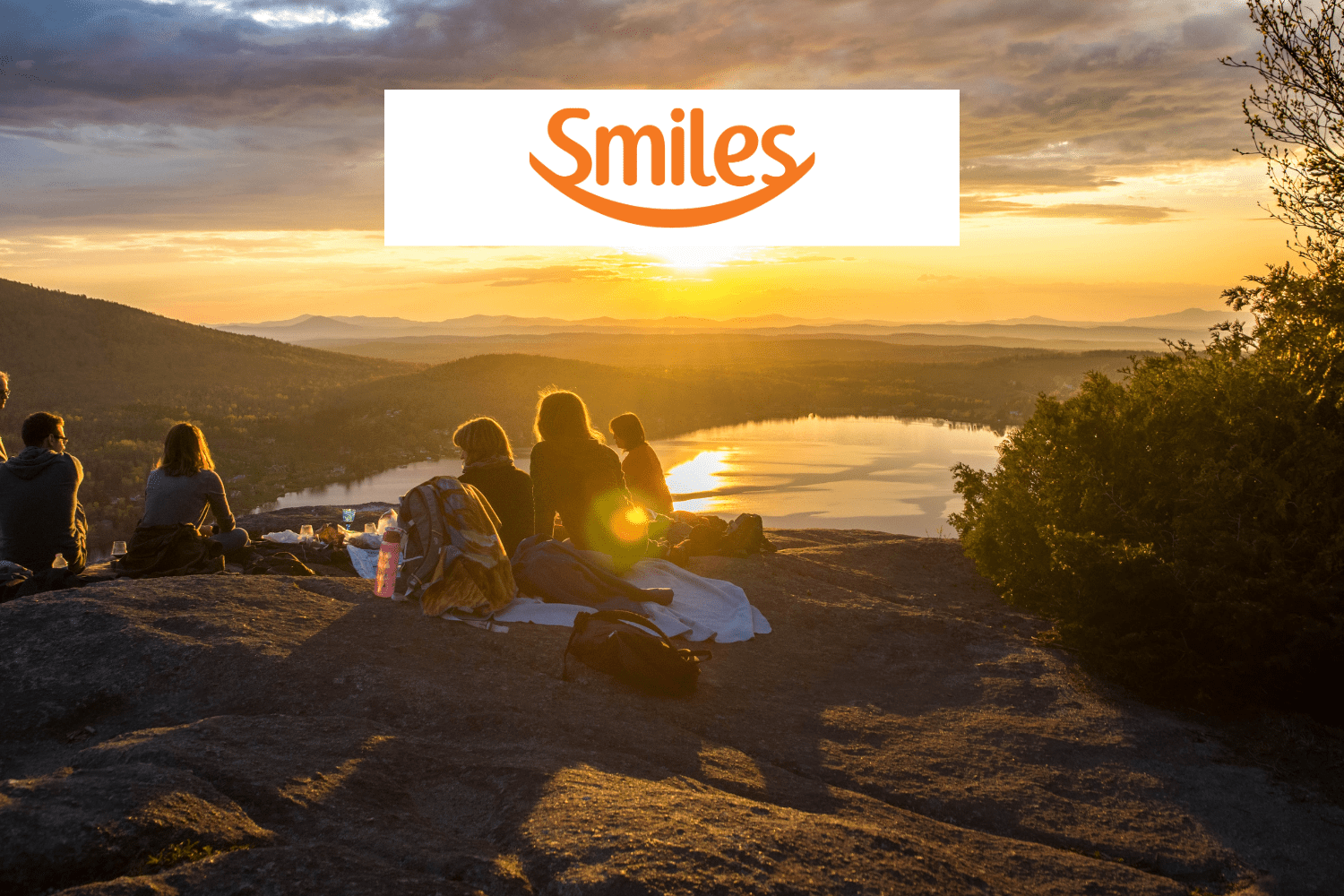 grupo de pessoas no topo de uma montanha olhando a vista com logo Smiles pontos Smiles