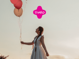 mulher branca segurando balões rosas com logo Clube Livelo