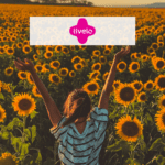 mulher feliz em um jardim de flores girassol com logo Livelo Pontos Livelo