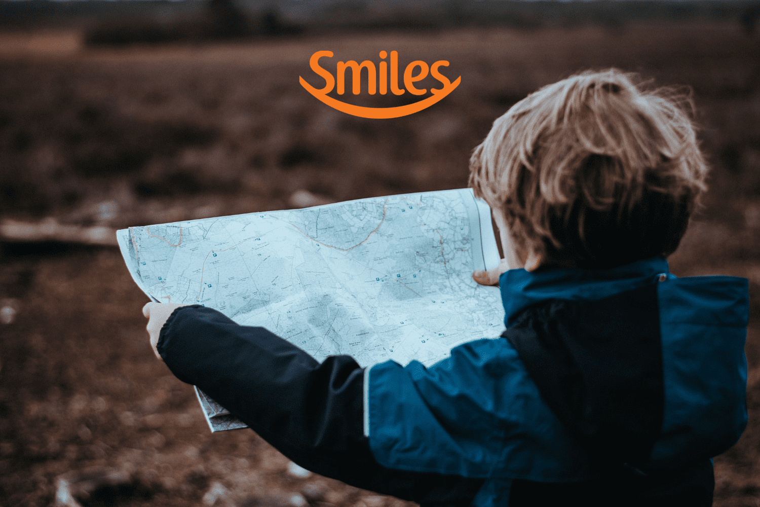 criança olhando um mapa com logo Smiles Clube Smiles
