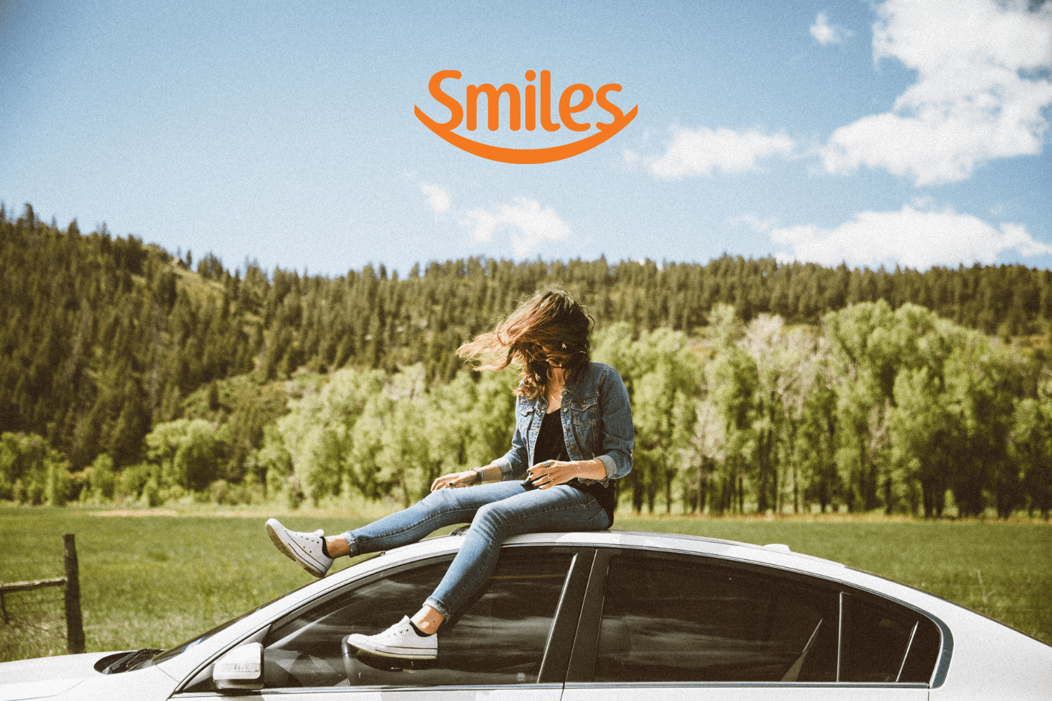 mulher em cima de um carro com logo Smiles Clube Smiles