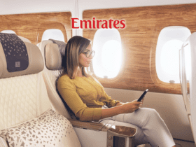 mulher loira de óculos mexendo no celular com logo Emirates