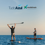 dois homens praticando stand up paddle no mar, com logo TudoAzul e Modalmais. bônus TudoAzul