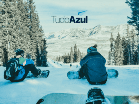 duas pessoas sentadas na neve com logo Clube TudoAzul