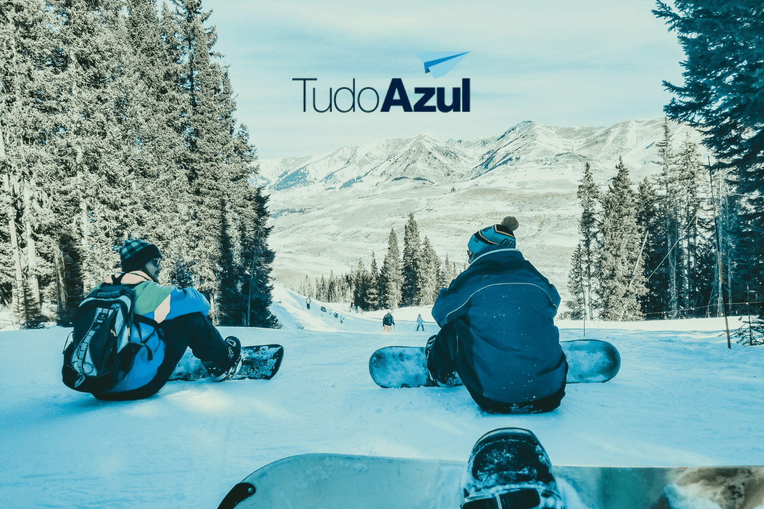 duas pessoas sentadas na neve com logo Clube TudoAzul