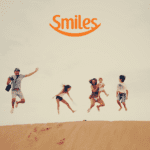 família pulando alegre sobre a areia com logo Clube Smiles