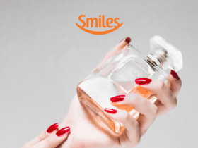 uma mão segurando um frasco de perfume com logo Smiles Pontos Smiles