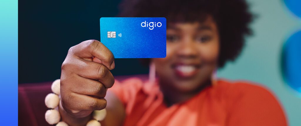 mulher preta sorrindo segurando um cartão de crédito Digio