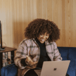mulher preta olhando feliz para um notebook melhores promoções