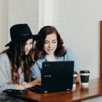 duas mulheres brancas olhando para um computador melhores promoções