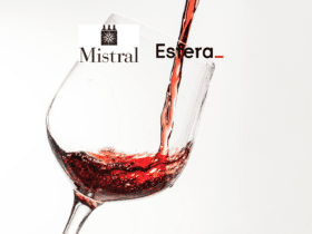 Vinho tinto sendo servido em uma taça transparente contra um fundo branco.