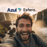 Homem sorridente tirando uma selfie em um cenário de cachoeiras com os logotipos da Azul e Esfera no topo da imagem. Ganhe 105% de bônus Azul com a Esfera.