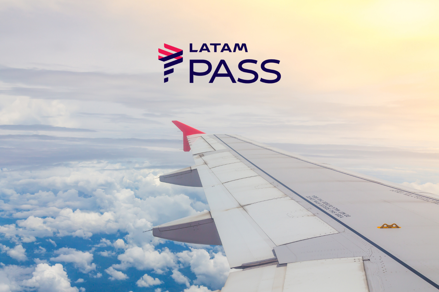 A imagem mostra a asa de um avião com uma ponta vermelha voando acima das nuvens. No canto superior direito, há o logotipo da LATAM Pass. O céu está parcialmente nublado, com o sol iluminando suavemente as nuvens. Pontos Latam Pass