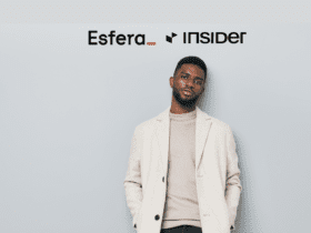 Homem vestindo um blazer claro sobre uma blusa de gola alta bege, em frente a um fundo cinza claro. Logotipos da Esfera e Insider estão posicionados acima dele.