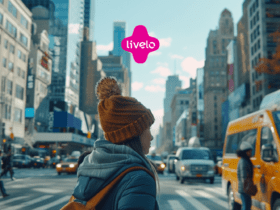 Pessoa com gorro marrom e casaco azul atravessando uma rua movimentada em uma cidade grande. Logotipo da Livelo no centro superior da imagem.