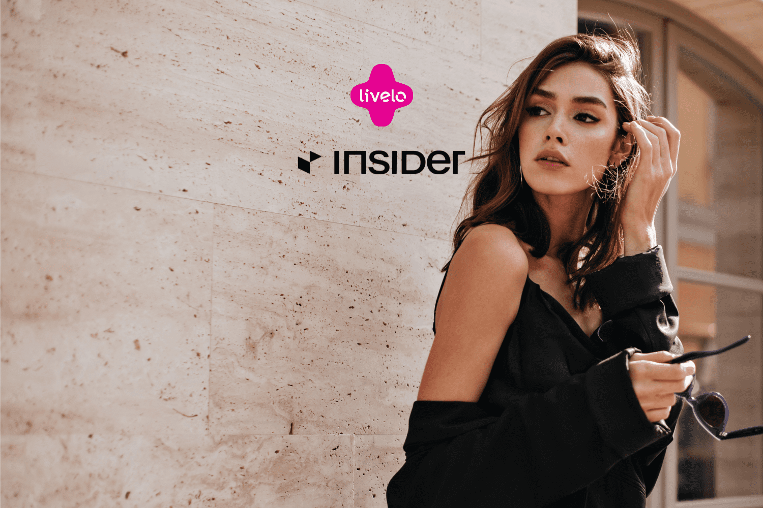 Mulher posando ao ar livre com um look sofisticado, acompanhada dos logos da Livelo e Insider. Ganhe 14 pontos Livelo com a Insider Store.