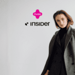 Imagem de uma mulher vestindo um casaco cinza, com os logotipos da Livelo e da Insider em destaque no centro. O fundo é branco e minimalista, destacando a elegância da roupa. Ganhe até 15 pontos Livelo com a Insider Store;