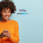 Imagem de uma jovem mulher sorrindo e segurando um smartphone. Ela está usando um suéter laranja brilhante e tem cabelo cacheado volumoso. O fundo é azul claro. A mulher olha para o lado com uma expressão alegre e confiante. No centro superior da imagem, estão os logos do LATAM Pass e do PortoPlus, sugerindo uma parceria entre as marcas