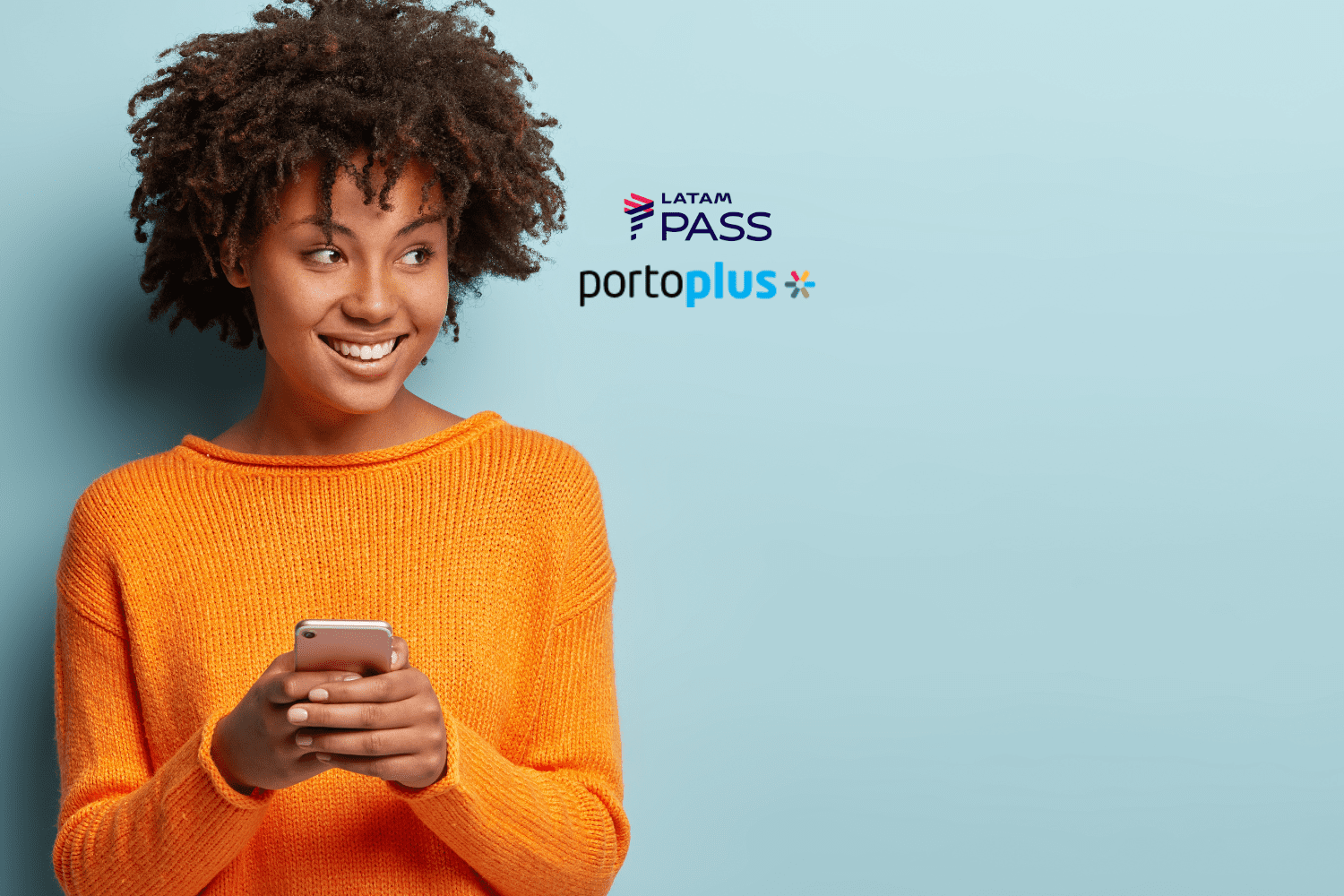 Imagem de uma jovem mulher sorrindo e segurando um smartphone. Ela está usando um suéter laranja brilhante e tem cabelo cacheado volumoso. O fundo é azul claro. A mulher olha para o lado com uma expressão alegre e confiante. No centro superior da imagem, estão os logos do LATAM Pass e do PortoPlus, sugerindo uma parceria entre as marcas