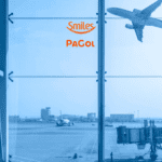 Imagem de um aeroporto vista de dentro, através de uma grande janela de vidro. No fundo, há um avião decolando e outro avião estacionado perto de um portão de embarque. O cenário é dominado por tons de azul, sugerindo um filtro ou iluminação específica. No centro superior da imagem, estão os logos da Smiles e da Pagol, sugerindo uma parceria entre as marcas.