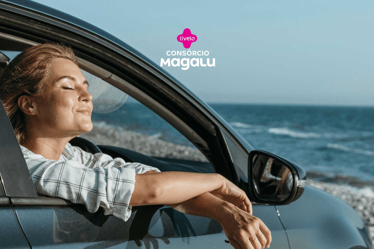 Na imagem, uma mulher está relaxando dentro de um carro, com a janela aberta, de frente para o mar. Ela está com os olhos fechados e um sorriso sereno no rosto, sentindo a brisa marítima. A mulher usa uma camisa xadrez de mangas longas arregaçadas. No fundo, vemos o mar azul e um céu claro. Na parte superior central da imagem, estão os logotipos das empresas Livelo e Consórcio Magalu.