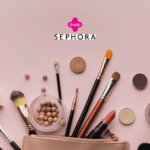 Conjunto de pincéis de maquiagem, batom, esponja e outros cosméticos dispostos sobre uma superfície rosa clara, ao lado de uma necessaire. Acima, estão os logos da Livelo e da Sephora, indicando uma colaboração de beleza e maquiagem.