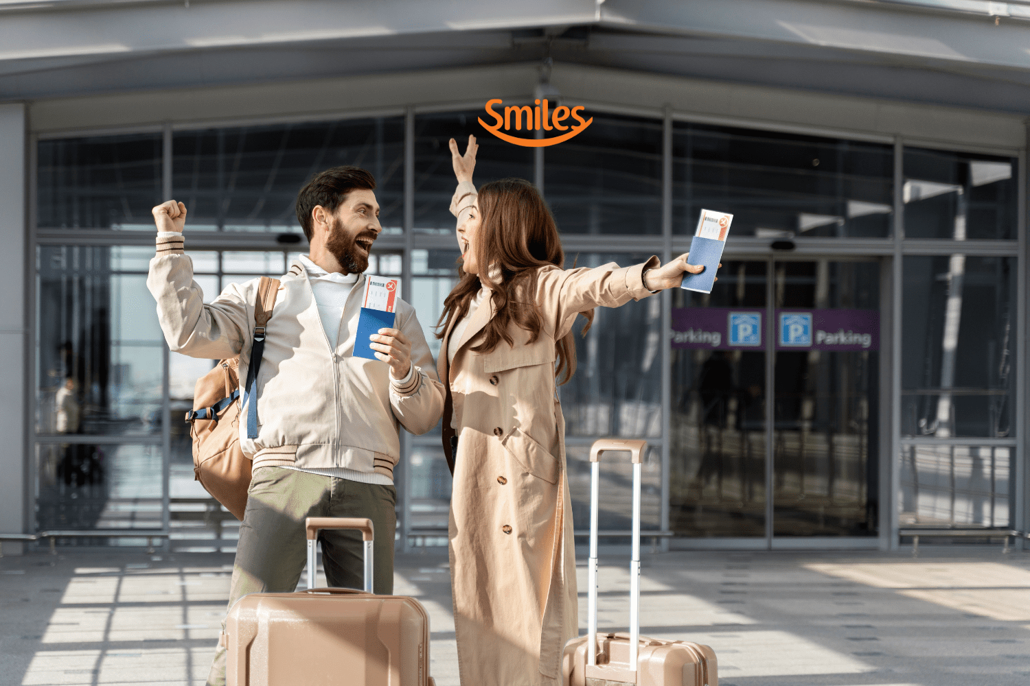 Casal sorridente em frente a um aeroporto, segurando passagens aéreas e levantando os braços em comemoração. Eles têm malas de viagem ao lado. Acima deles está o logo da Smiles, indicando uma viagem feliz e recompensadora.